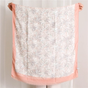 Détail d'un châle en coton et lin fleuri avec bords orange et motifs de feuilles