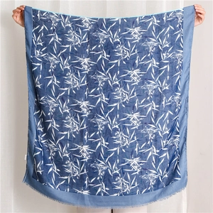 Détail d'un châle bleu avec imprimé de feuilles blanches et bords à franges fins
