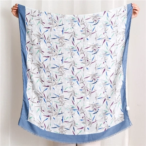 Détail d'une écharpe en coton blanc avec imprimé floral bleu et bords effilochés