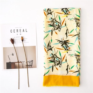 Détail d'une écharpe en lin avec motifs de feuilles et bords à franges jaunes
