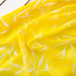 Gros plan d'une écharpe jaune avec motifs de feuilles montrant la texture du tissu