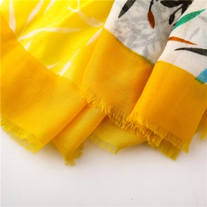 Gros plan d'une écharpe en coton lin jaune avec motif floral et bordures à franges