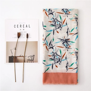 Détail d'une écharpe en lin avec imprimé floral, texture fine et bords à franges doux
