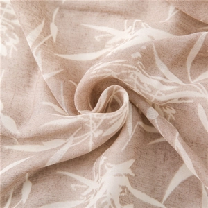Vue détaillée d'une écharpe en coton et lin avec motifs de feuilles blanches et texture