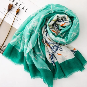 Détail de l'écharpe en coton vert menthe avec imprimé floral et bords effilochés doux