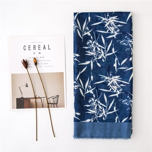 Détail d'une écharpe en coton et lin bleu marine avec motif de bambou blanc et franges