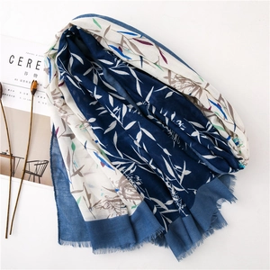 Détail de l'écharpe en coton bleu et blanc avec motif de feuilles colorées et bords effilochés