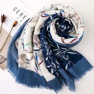 Mise en scène d'un châle en lin bleu marine et blanc avec motifs floraux et bords effilochés