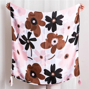Detail of floral print scarf featuring pink tassel trim and light linen texture