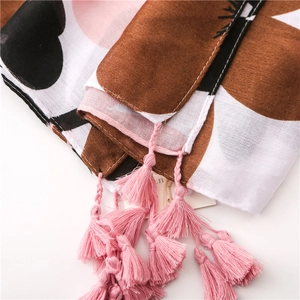 Detail of floral printed scarf showing light cotton texture and pink tassel trim
