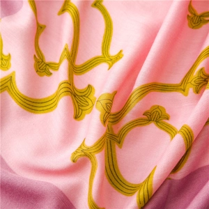 Détail d'écharpe rose en coton et lin montrant des motifs baroques jaunes et une texture douce