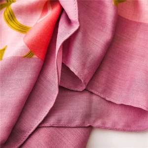 Gros plan d'une écharpe rose en coton et lin avec texture douce et motifs floraux