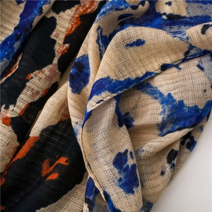 Macro detail of breathable cotton linen scarf showing abstract navy and orange print texture