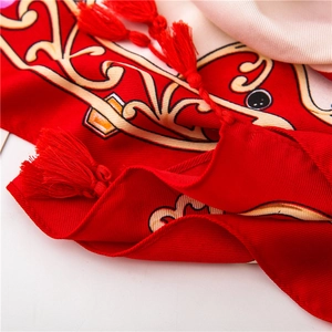 Detail of red twill scarf featuring elegant horse carriage prints and fine woven tassels