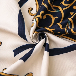 Close-up of printed twill scarf showing golden baroque pattern and silk-like texture