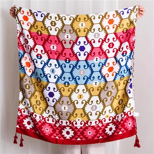 Detailed close-up of ethnic geometric pattern shawl with red tassel ornaments