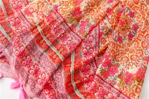 Detail of vibrant floral ethnic scarf featuring pink tassels and bohemian print fabric
