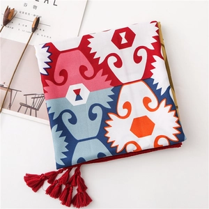 Detailed view of colorful ethnic pattern scarf with red tassel trim on white desk