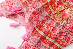 Detailed macro view of pink bohemian floral print fabric and decorative edge tassels