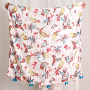 Detail of tropical scarf with colorful parrot prints and alternating yarn tassels