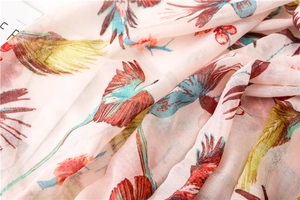 Close-up of pink sun shawl fabric showing colorful bird patterns and soft silk texture