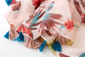 Detail of pink floral scarf showing gold threads and colorful tassel fringe edge
