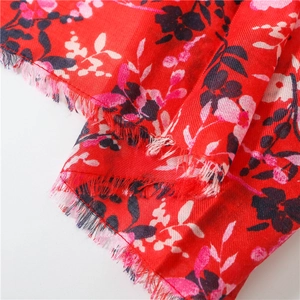 Close-up of red cotton linen scarf with floral print and detailed fringe edge