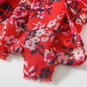 Detailed macro view of red floral cotton linen scarf with soft fringed edges