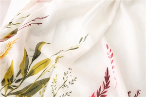 Detail of white cotton linen scarf featuring colorful floral print and soft fabric texture