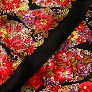 Detailed close-up of intricate red floral and berry patterns on black twill fabric scarf
