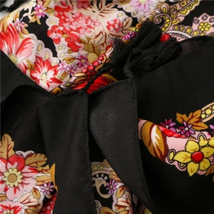 Macro detail of black floral scarf with paisley patterns, silk texture and fringe trim
