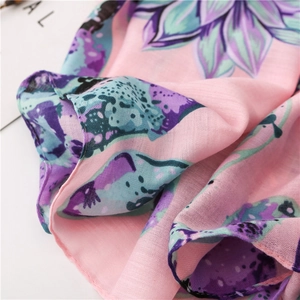 Gros plan détaillé du foulard floral rose montrant la texture légère et les bords surjetés