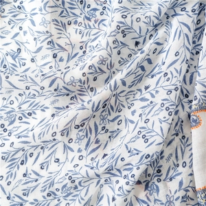 Macro detail of soft cotton scarf featuring blue paisley floral print on white fabric
