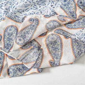 Detailed close-up of paisley pattern on white soft cotton scarf with orange and blue accents