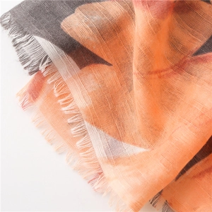 Detail eines dünnen Baumwollleinen Schals mit abstraktem Druck in Orange und Grau Fransen