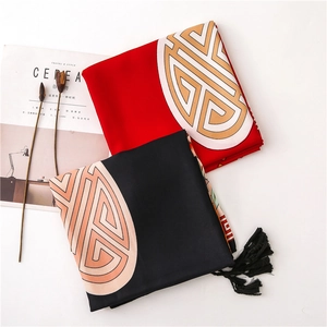 Close-up of red and black cotton linen scarves with golden totems and long black tassels