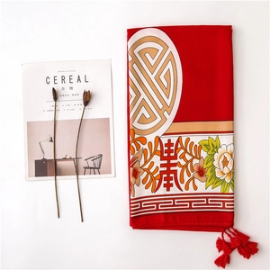 Detail of red silk scarf with traditional floral patterns and decorative fringe edges
