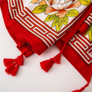 Close-up of red cotton linen scarf with peony pattern, fret border, and tassels