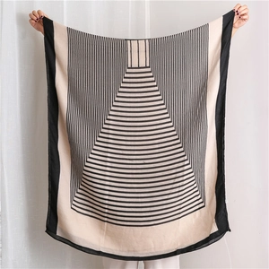 Détail d'une écharpe tissée fine à rayures beige et noir avec large bordure