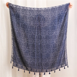Détail d'une écharpe en coton bleu marine avec pois blancs et décorations de glands