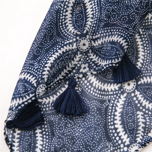 Gros plan d'une écharpe en coton et lin à motif floral bleu avec des détails de glands