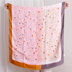 Détail d'une écharpe géométrique à carreaux rose et orange avec bords effilochés