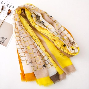 Détail d'une écharpe à motifs géométriques jaunes avec texture douce et franges