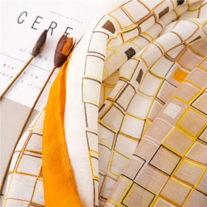 Gros plan d'une écharpe en coton et lin avec motif à carreaux orange et texture tissée