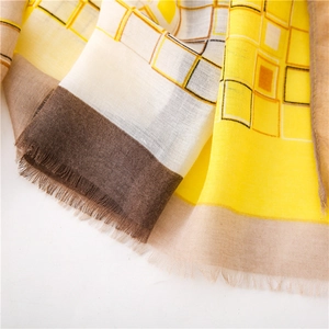 Détail d'une écharpe à motifs géométriques jaunes et marron avec bords à franges