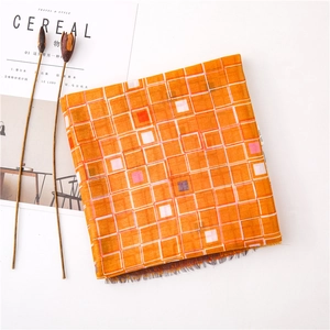 Détail de l'écharpe à carreaux orange avec franges sur table blanche avec un magazine