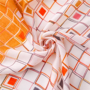 Gros plan sur le motif à carreaux géométriques d'une écharpe en coton et lin orange vif