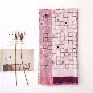 Vue détaillée d'une écharpe à carreaux rose et violette avec de fines franges sur fond blanc