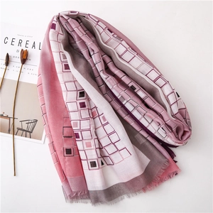 Détail d'une écharpe à motifs géométriques roses et gris avec des franges délicates