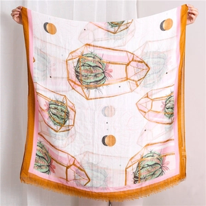 Detail view of a lightweight white scarf with cactus prints and yellow tasseled edges